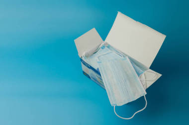 外科保護(hù)膜。醫(yī)用呼吸繃帶盒面對(duì)藍(lán)色背景的口罩短缺。預(yù)防病毒和大流行病COVID-19的傳播