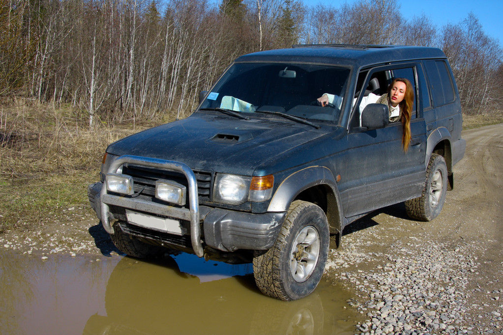 年轻女子越野汽车前水障碍的土路上的方向舵背后 年轻女子越野汽车前水障碍的土路上的方向舵背后