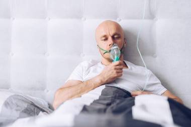 男人在床上通過氧氣罩呼吸。Covid-19病人