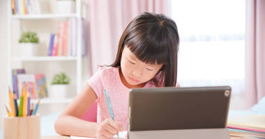 亞洲女學(xué)生在家里用平板電腦愉快地上網(wǎng)上課