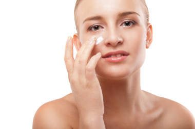 女人在孤立的臉上應(yīng)用保濕霜圖片