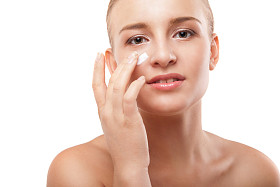 女人在孤立的脸上应用保湿霜图片