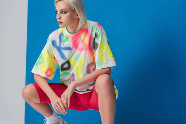 穿著霓虹燈粉色自行車短褲和灰色和藍(lán)色色彩艷麗的T恤衫的時(shí)髦女人 