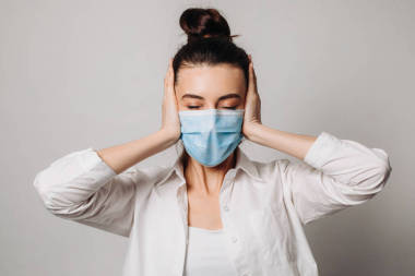 情緒震驚的女醫(yī)務(wù)人員戴著外科口罩，由于大流行病的威脅而陷入恐