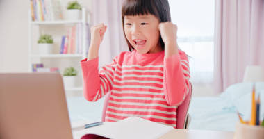 亞洲女學(xué)生感到很興奮，很高興用筆記本電腦在家里愉快地上網(wǎng)上課