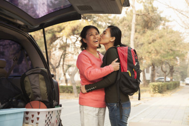 母親和女兒擁抱在大學校園里的車的后面