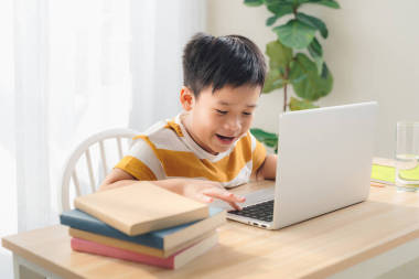 小學生們在家里的桌旁用筆記本電腦玩網絡游戲，有十四天的空閑時間