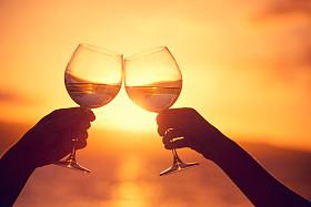 男人和女人叮叮当当日落 dra 香槟的酒杯