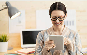 在家里的笔记本电脑上工作的快乐而随意的漂亮女人