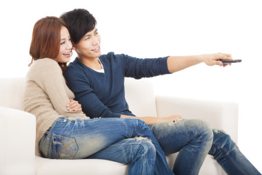 年輕的夫婦，在沙發(fā)上看電視與遠(yuǎn)程控制