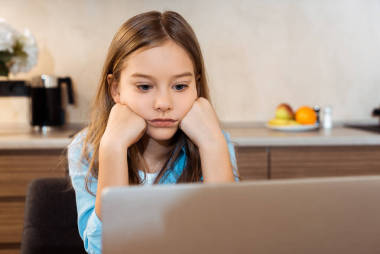 网上学习和在家看笔记本电脑的无聊孩子的选择焦点