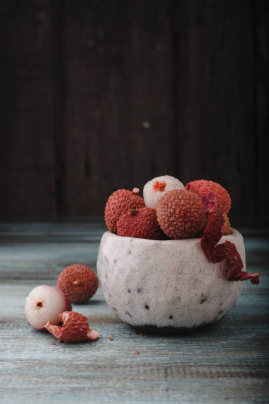 具有复制空间的中国荔枝。新鲜的荔枝水果在一个碗里，在古老的乡村木质背景下。生红的有机荔枝果，可供食用