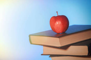 桌上一堆舊書上的紅蘋果.圖片