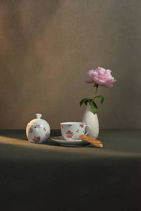 茶杯，茶碟和曲奇饼，糖碗，白色花瓶，还有牡丹，放在清晨阳光下灰色房间的桌子上
