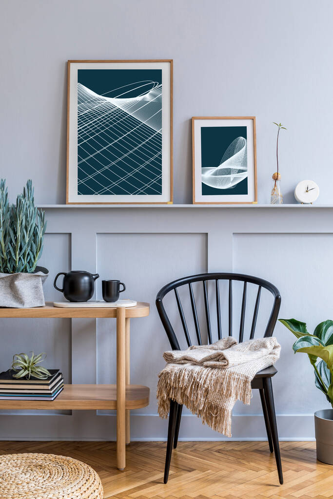 时尚的丑闻在鸟类客厅的内部设计黑色椅子，木制控制台，植物，书籍，装饰，模型海报架在架子上和雅致的配件在现代家居装饰