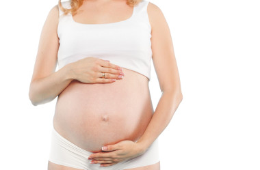 孕婦拿著的紅色小鞋子?jì)雰弘p紅色背景上的肖像。工作室