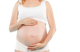 孕妇拿着的红色小鞋子婴儿双红色背景上的肖像。工作室
