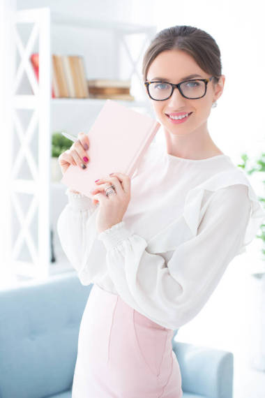 辦公室里拿著眼鏡和筆記本的現(xiàn)代女商人。這個女孩穿著雅致的西服、裙子和襯衫。女老板，女商人