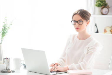 一個(gè)年輕的女人在辦公桌前工作，辦公室里有一臺(tái)筆記本電腦。婦女事務(wù)，遠(yuǎn)程工作