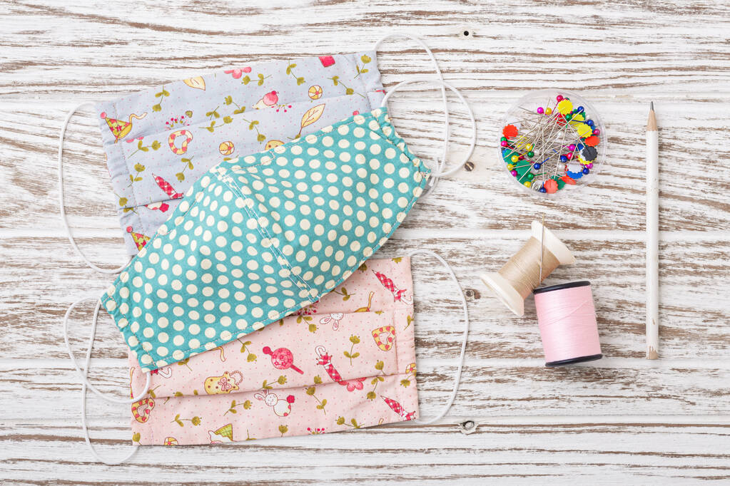 DIY织物面罩与缝纫配件在乡村白色木桌上。验尸官的保护膜 DIY织物面罩与缝纫配件在乡村白色木桌上。验尸官的保护膜