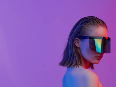 在明亮的霓虹燈背景上擺出時(shí)尚的發(fā)型，戴著時(shí)髦的眼鏡，戴著大玻璃杯的時(shí)尚女孩