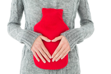 一個(gè)女人在肚子里的熱水袋里拿著紅色的團(tuán)結(jié)