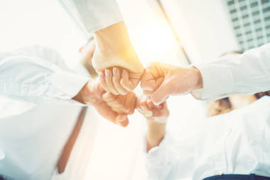 在陽光燦爛的背景下，商人們用拳頭致意