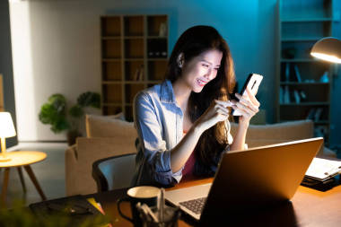 亞洲女商人使用智能手機(jī)和筆記本電腦在家工作