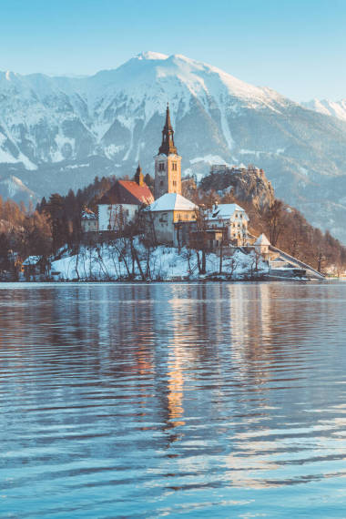 著名的布莱德岛（布莱斯基奥托克）在风景秀丽的布莱德湖与布莱德城堡（布莱斯基格勒）和朱利安阿尔卑斯山在背景在金色的晨光在冬天的日出，斯洛文尼亚的美丽景色