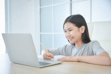 十幾歲以下的亞洲女學(xué)生在家里帶著筆記本電腦上網(wǎng)學(xué)習(xí)。兒童的教育和遠距離學(xué)習(xí)。檢疫期間的家教. 
