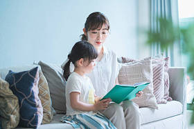母亲和女儿坐在沙发上看画册图片