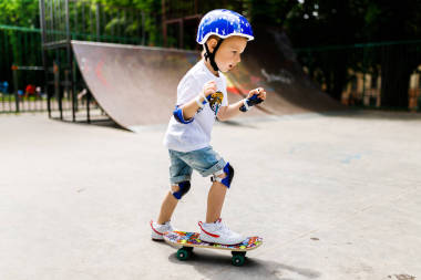 在溜冰場(chǎng)里玩溜冰鞋的男孩。這個(gè)男孩在充分保護(hù)下學(xué)會(huì)了滑冰