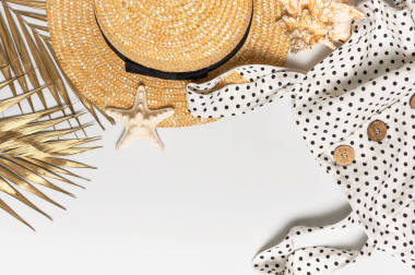 夏天妇女的白色衣服黑色豌豆与天然木制纽扣草帽金棕榈叶壳海星淡淡的背景。平面放置顶部视图复制空间。女子海滩时尚旅游度假
