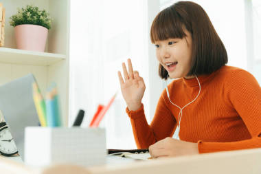 年輕美麗的亞裔黑發(fā)女子在家里學(xué)習(xí)，在網(wǎng)上用筆記本電腦和耳機(jī)學(xué)習(xí)。好姿勢擺姿勢