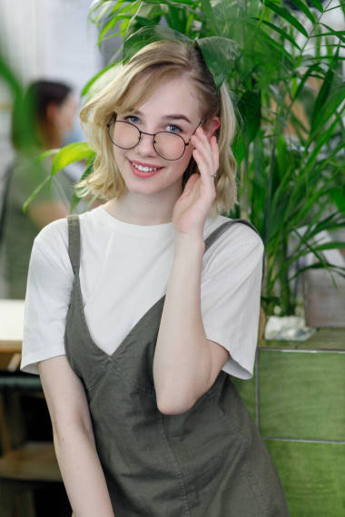 在舒適的綠色咖啡館里，穿著華麗衣服的年輕而快樂(lè)的女性在鏡頭前與綠葉相映成趣。戴眼鏡的女孩