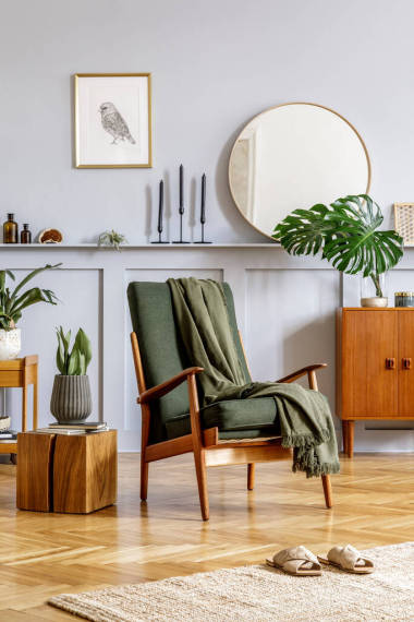 客厅内饰时尚时尚，有设计扶手椅、木制复古梳妆台、圆形镜子、架子、热带叶、咖啡桌、装饰、地毯和室内装饰的汗流浃背饰