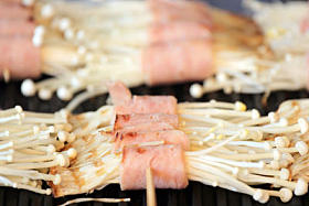 金针菇蘑菇和烤架上培根.图片