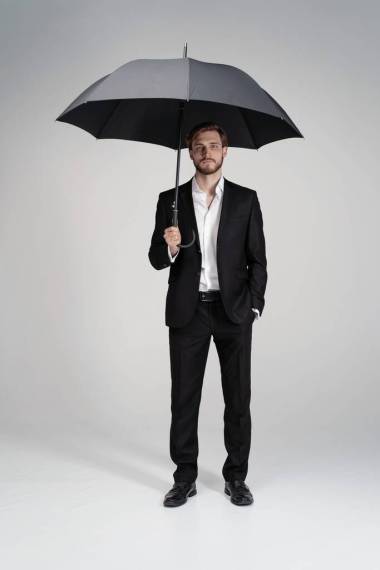 穿著西服站在黑色雨傘下的商人