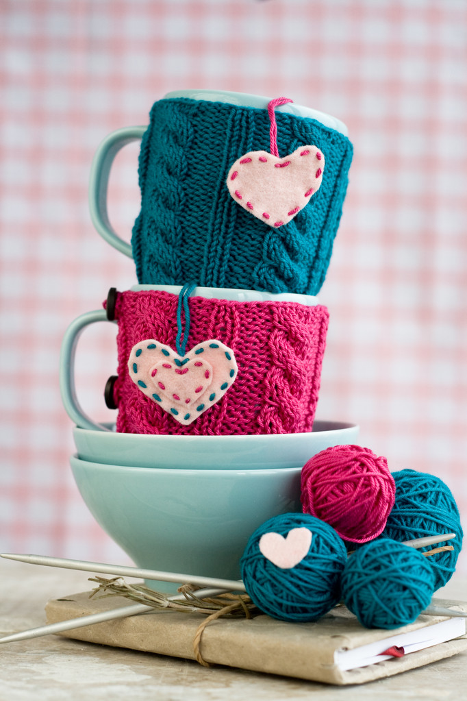 两个青的杯子，在蓝色和粉红色的毛衣，配毛毡的心