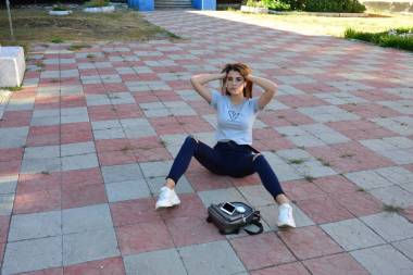 年輕而快樂的嬉皮士年輕女人穿著時(shí)髦的夏裝坐在鄉(xiāng)間的路上。包。溫暖的夜晚色彩。孫先生