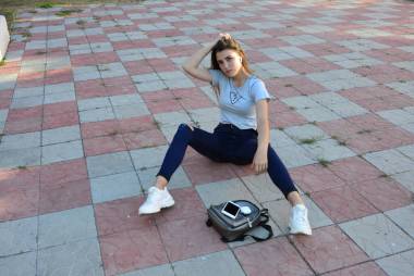 年轻而快乐的嬉皮士年轻女人穿着时髦的夏装坐在乡间的路上。包。温暖的夜晚色彩。孙先生