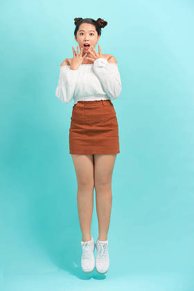 美丽而兴奋的少女，双手高举在脸上。笑着看着镜头。与蓝色背景隔离