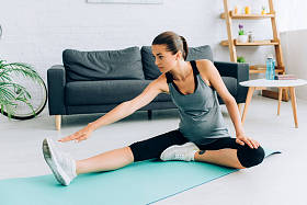 年轻孕妇坐在健身垫上做伸展运动