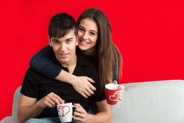 与坐在沙发上的杯子对可爱的夫妇的肖像