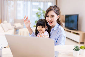 亚洲的年轻女子和她的女儿愉快地通过笔记本电脑进行视频聊天