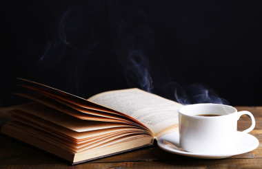 杯熱咖啡，在深色背景上的桌子上的書(shū)