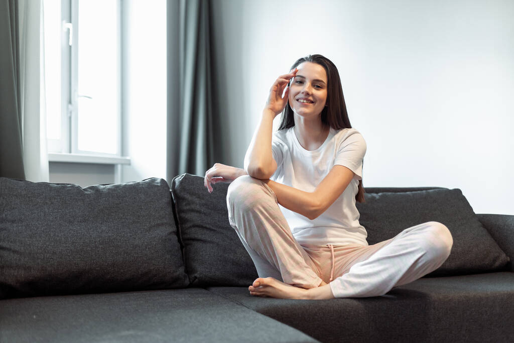 年轻女人在客厅的沙发上很放松。随意式室内拍摄