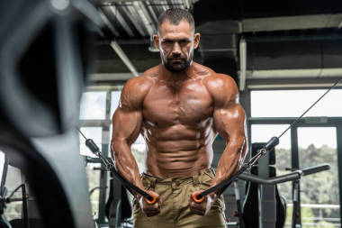 在運動健身中心做大量舉重運動的有吸引力的高個子肌肉健美運動員