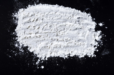 灑在黑色的木桌上的白面粉.圖片