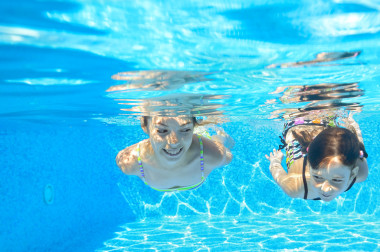 快樂女生水下在游泳池里游泳